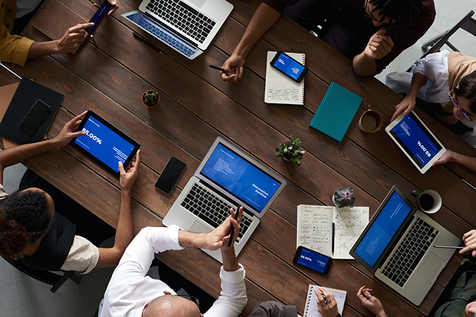 Team collaborating around a table with laptops and devices